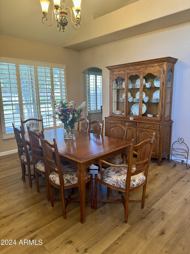 dining area with a chandelier, light hardwood / wood-style floors, and lofted ceiling