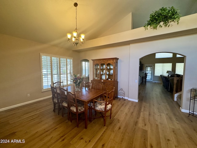 dining area with hardwood / wood-style flooring, high vaulted ceiling, and a notable chandelier