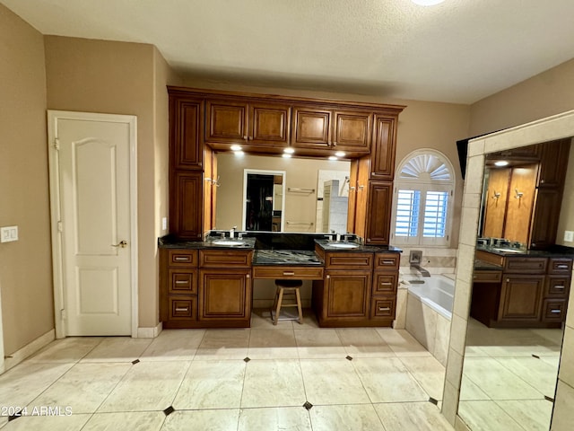 bathroom with tile patterned flooring, vanity, and a relaxing tiled tub