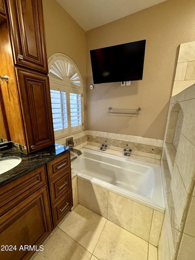 bathroom featuring tile patterned floors, a relaxing tiled tub, and vanity