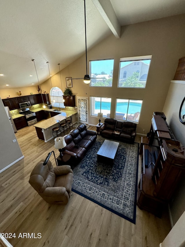 living room with beam ceiling, high vaulted ceiling, and light hardwood / wood-style flooring