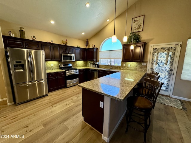 kitchen with sink, tasteful backsplash, decorative light fixtures, light stone counters, and stainless steel appliances