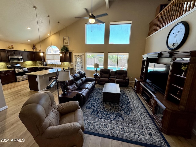 living room with ceiling fan, high vaulted ceiling, and light hardwood / wood-style flooring