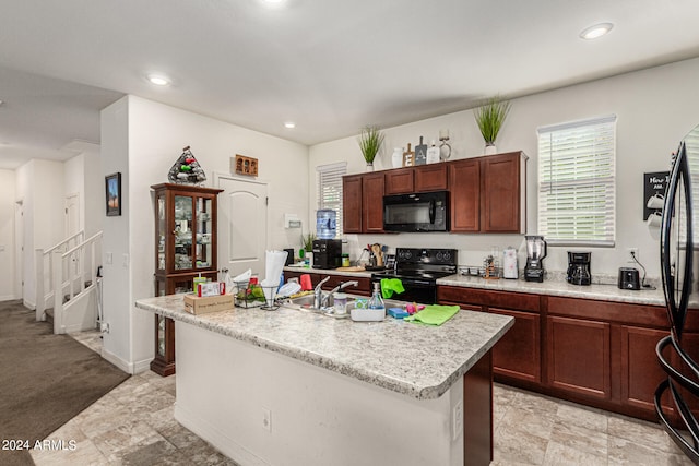 kitchen featuring black appliances, a kitchen island with sink, and sink