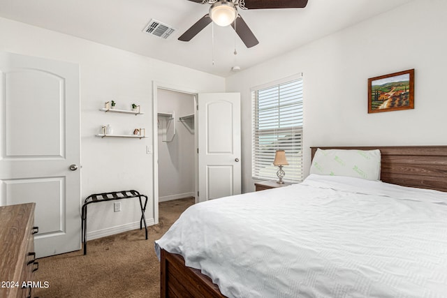 carpeted bedroom with a spacious closet, a closet, and ceiling fan