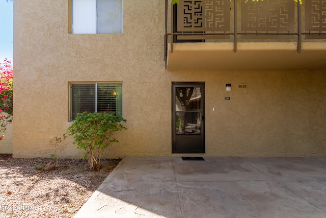 view of exterior entry with a patio area and a balcony