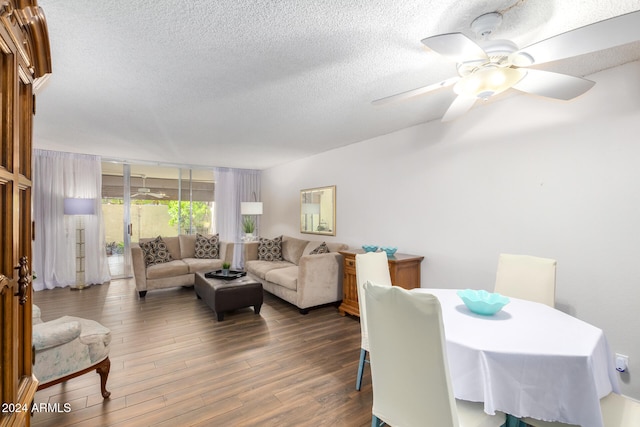 living room with a textured ceiling, ceiling fan, and dark hardwood / wood-style floors