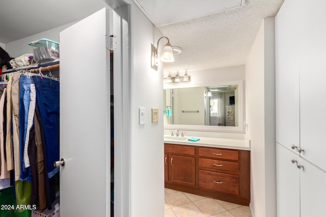 bathroom with tile patterned flooring, vanity, and a textured ceiling