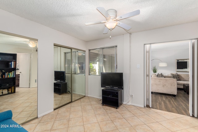 living room with ceiling fan, a textured ceiling, and light hardwood / wood-style flooring