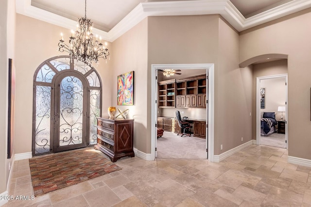 foyer featuring a raised ceiling, ornamental molding, a towering ceiling, and ceiling fan