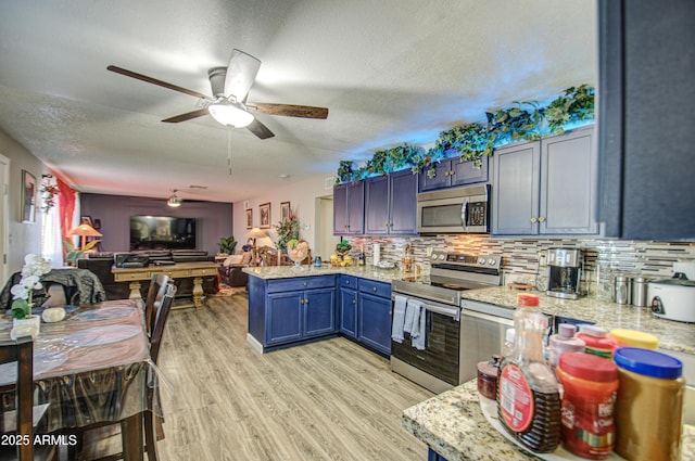 kitchen featuring stainless steel appliances, kitchen peninsula, ceiling fan, decorative backsplash, and blue cabinets