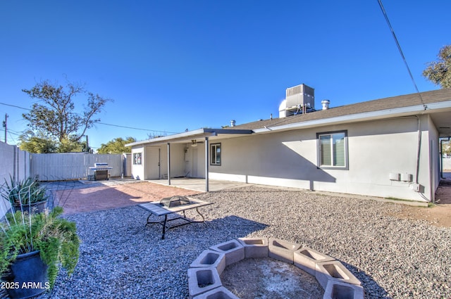 rear view of property with a patio, central air condition unit, and a fire pit