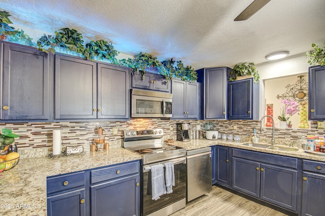 kitchen with appliances with stainless steel finishes, light hardwood / wood-style floors, decorative backsplash, and sink