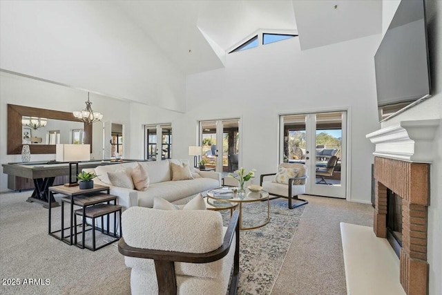 carpeted living room with french doors, a fireplace, high vaulted ceiling, and a notable chandelier