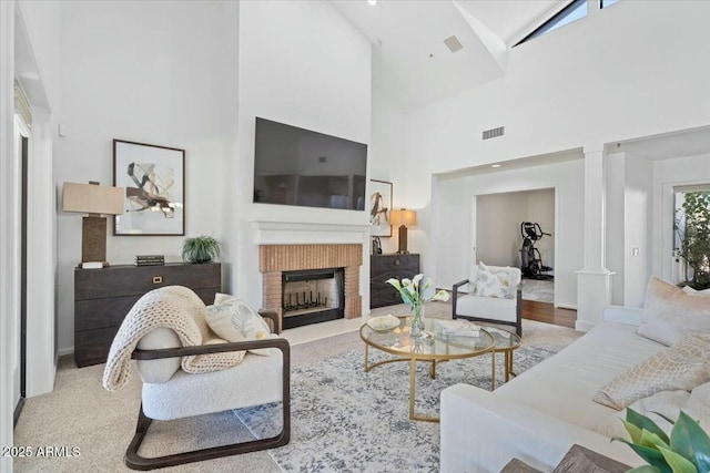 living room with decorative columns, a brick fireplace, a wealth of natural light, and high vaulted ceiling