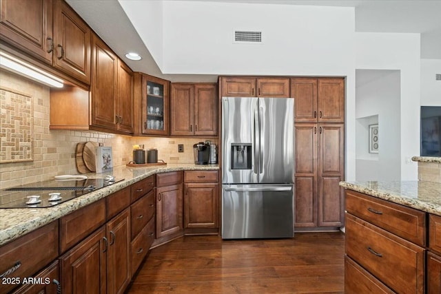 kitchen with tasteful backsplash, light stone counters, stainless steel refrigerator with ice dispenser, dark wood-type flooring, and black electric cooktop