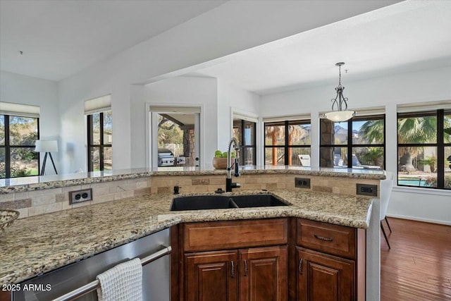 kitchen with sink, light stone counters, decorative light fixtures, dark hardwood / wood-style floors, and dishwasher