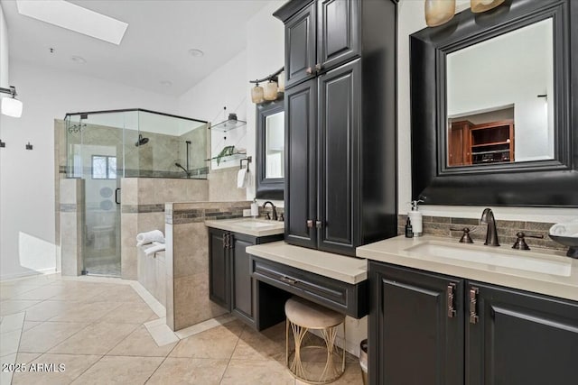 bathroom featuring a skylight, vanity, an enclosed shower, and tile patterned flooring