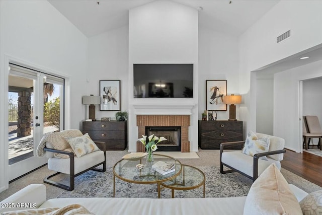 living room featuring french doors, a fireplace, high vaulted ceiling, and light hardwood / wood-style flooring