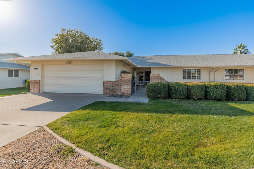 ranch-style home featuring a garage and a front lawn