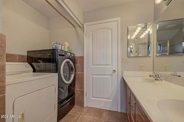 washroom featuring light tile patterned floors, washing machine and dryer, and sink