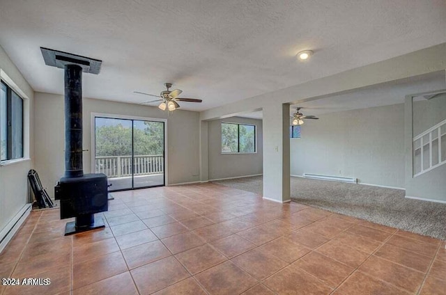 interior space with light tile patterned floors, a textured ceiling, a wood stove, and a baseboard radiator