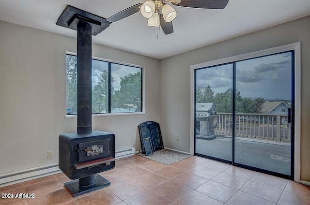 interior space featuring ceiling fan, a wood stove, and a baseboard radiator