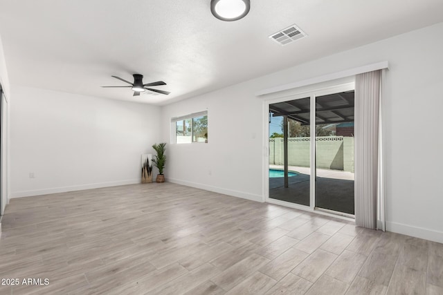 spare room featuring light wood-style flooring, ceiling fan, baseboards, and visible vents