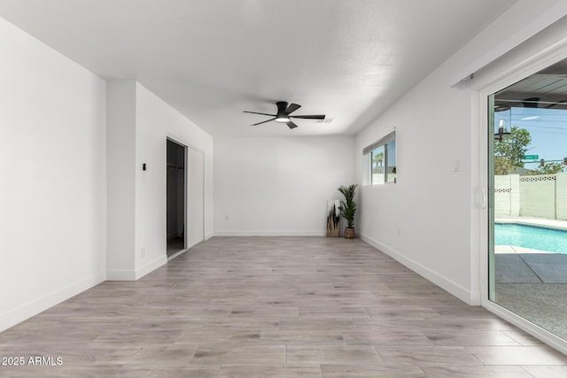 spare room featuring visible vents, ceiling fan, light wood finished floors, and baseboards