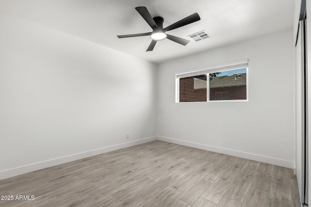 unfurnished room with baseboards, visible vents, light wood-type flooring, and a ceiling fan