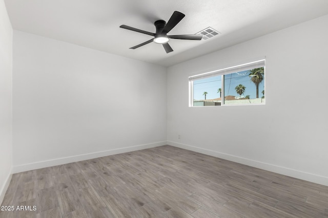 unfurnished room with ceiling fan, visible vents, baseboards, and wood finished floors