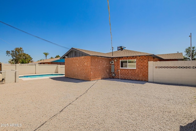 view of front of house with a fenced in pool, a patio area, brick siding, and a fenced backyard