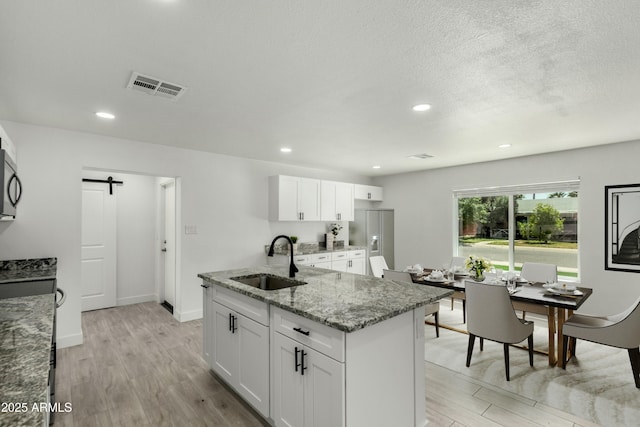 kitchen with light wood finished floors, visible vents, a sink, and a barn door