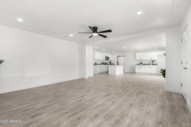 unfurnished living room featuring a ceiling fan, baseboards, recessed lighting, and light wood-style flooring
