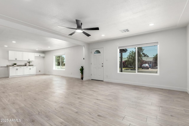 unfurnished living room featuring light wood finished floors, ceiling fan, and baseboards