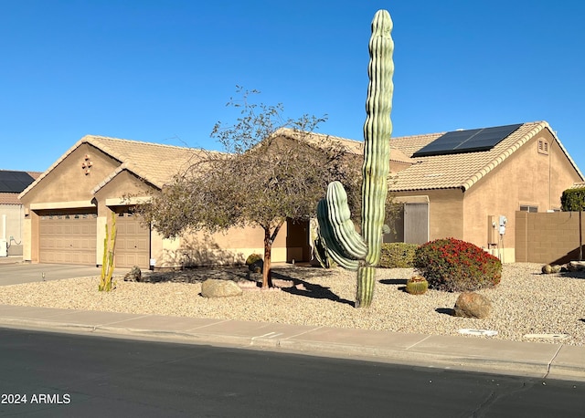 view of front of property featuring solar panels and a garage