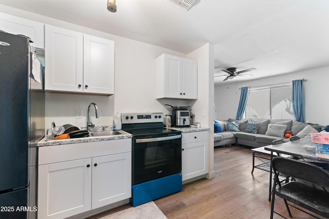 kitchen with electric range, ceiling fan, black refrigerator, and white cabinets