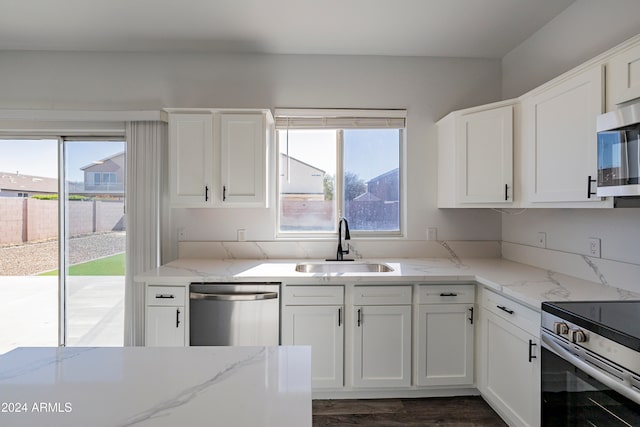 kitchen with light stone counters, white cabinetry, appliances with stainless steel finishes, dark hardwood / wood-style flooring, and sink