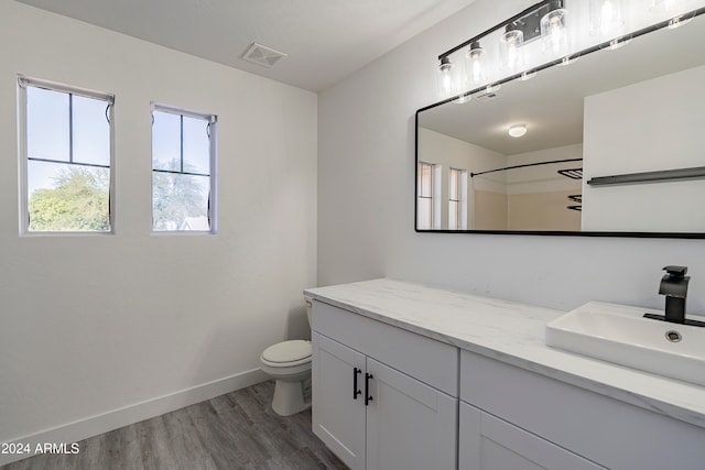 bathroom featuring a shower, wood-type flooring, vanity, and toilet