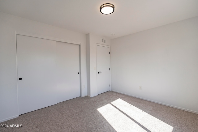 unfurnished bedroom featuring light carpet and a closet