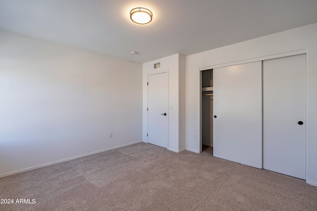 unfurnished bedroom featuring light colored carpet and a closet