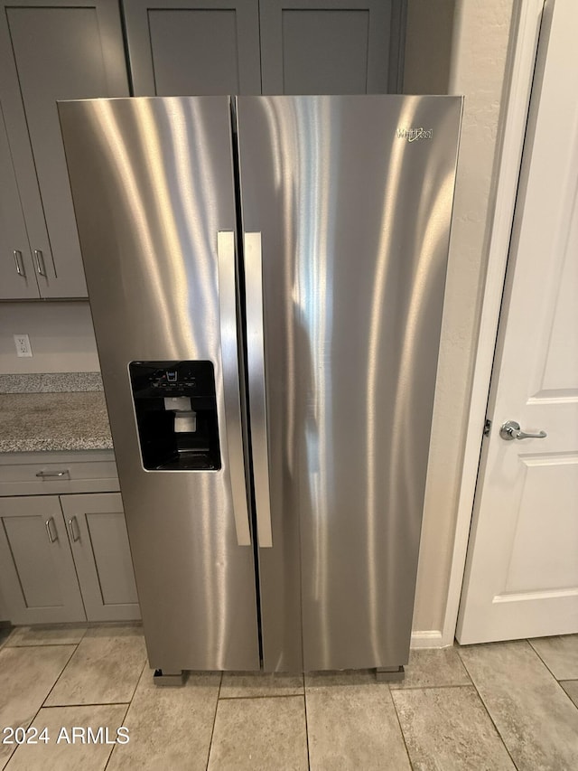 details featuring stainless steel refrigerator with ice dispenser, gray cabinets, and dark stone countertops