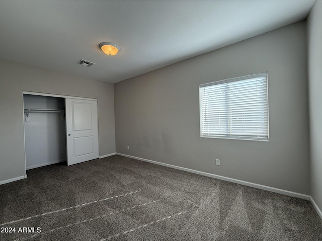 unfurnished bedroom featuring a closet and dark carpet