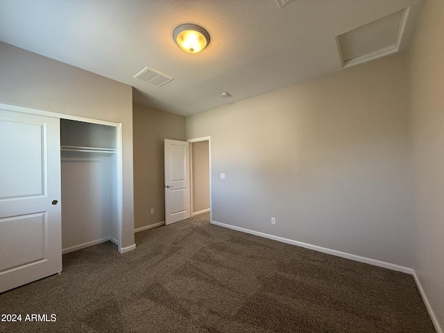 unfurnished bedroom featuring dark colored carpet and a closet