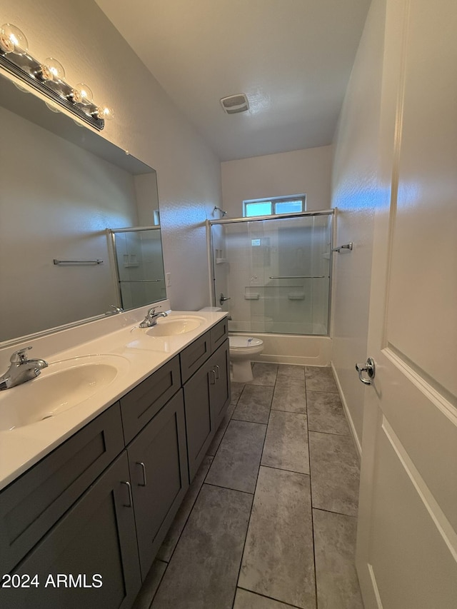 full bathroom featuring shower / bath combination with glass door, vanity, tile patterned flooring, and toilet