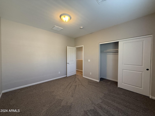 unfurnished bedroom with a closet and dark carpet