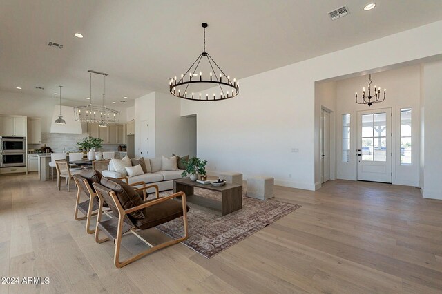 living room with light wood-type flooring and an inviting chandelier