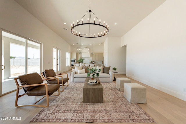 living room with light hardwood / wood-style flooring, a high ceiling, and an inviting chandelier