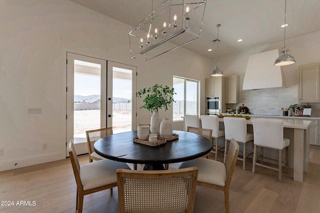 dining area with french doors, a towering ceiling, a mountain view, and light hardwood / wood-style flooring