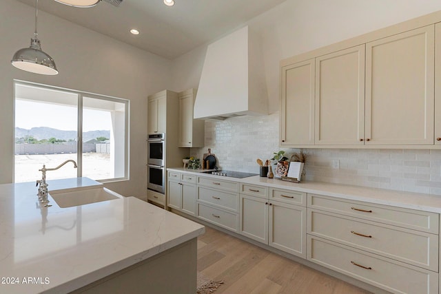 kitchen featuring premium range hood, sink, hanging light fixtures, a mountain view, and light stone countertops